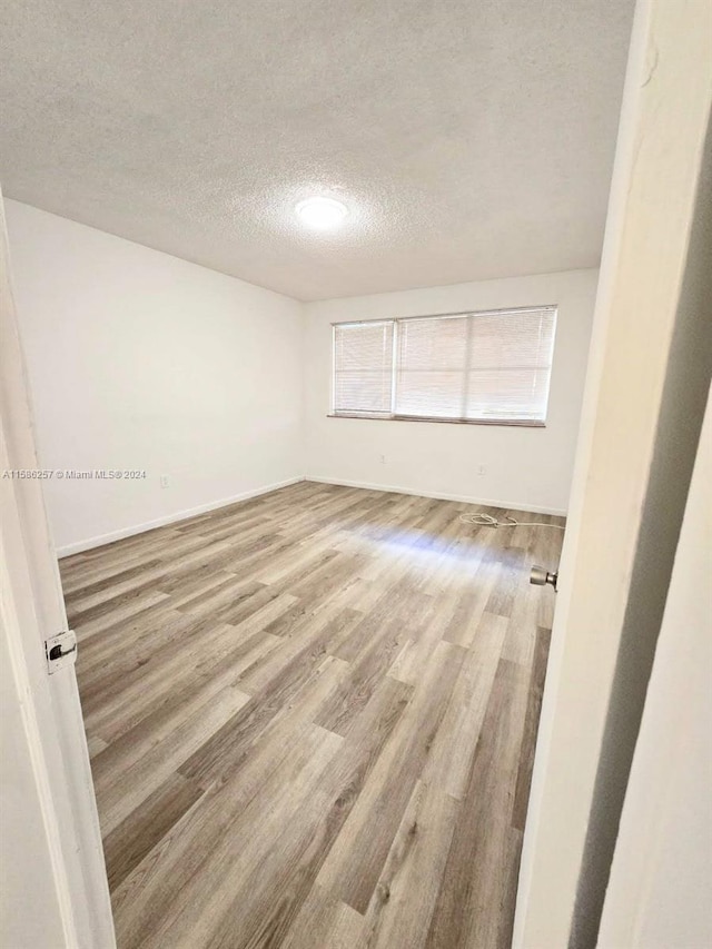 spare room with hardwood / wood-style floors and a textured ceiling