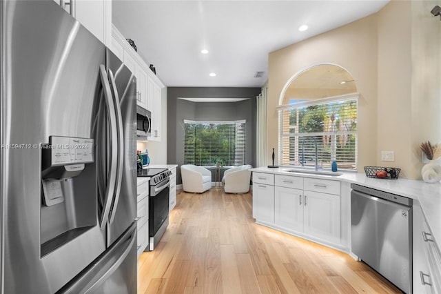 kitchen featuring white cabinetry, light hardwood / wood-style flooring, appliances with stainless steel finishes, and sink