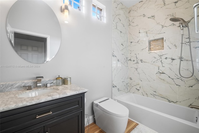 full bathroom featuring vanity, tiled shower / bath combo, wood-type flooring, and toilet