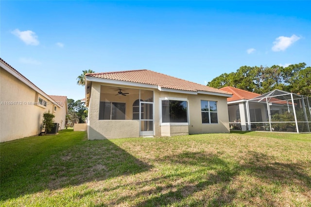 rear view of house with a lanai, ceiling fan, and a lawn