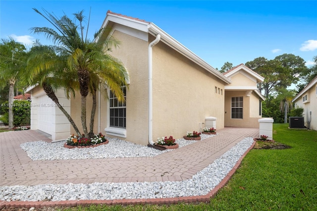 back of property with a garage, central AC, and a yard