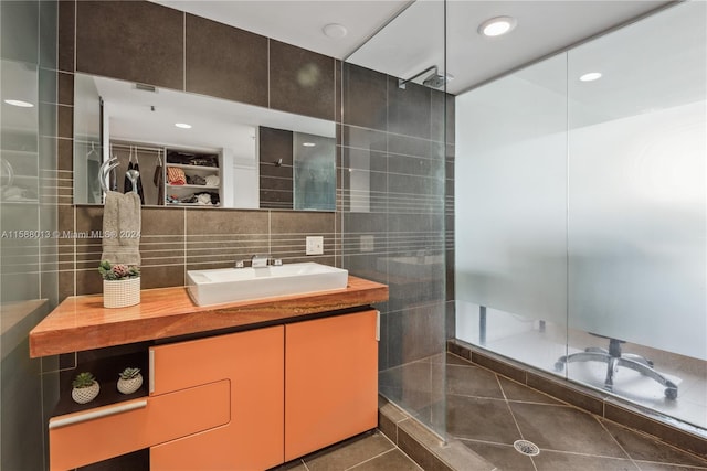 bathroom featuring a shower, vanity, tile patterned floors, and tile walls