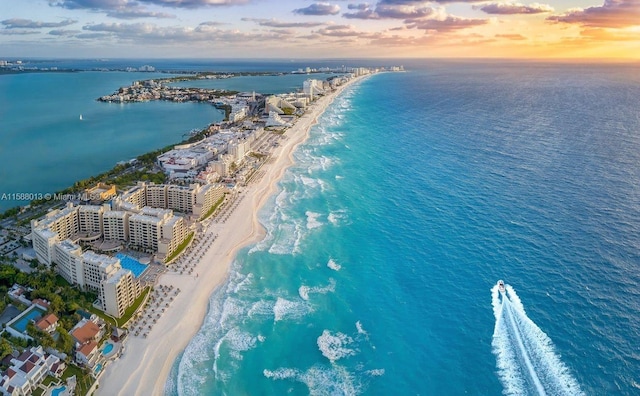 aerial view at dusk with a view of the beach and a water view