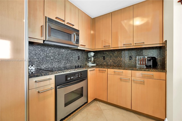 kitchen with decorative backsplash, stainless steel appliances, light tile patterned flooring, and dark stone countertops