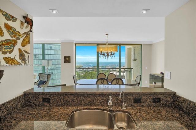 kitchen with pendant lighting, dark stone counters, plenty of natural light, and a notable chandelier