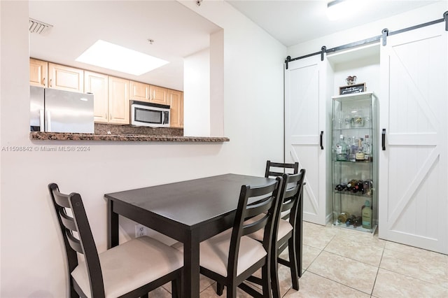 dining area featuring a barn door and light tile floors