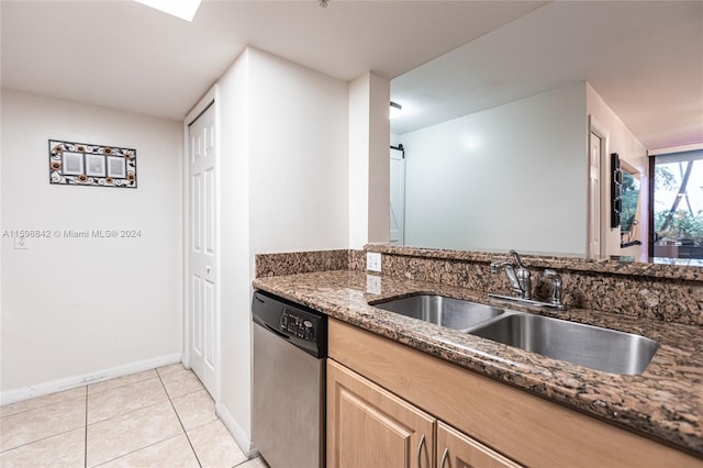 kitchen with dark stone countertops, sink, stainless steel dishwasher, and light tile flooring