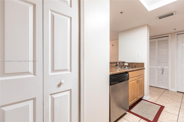 kitchen featuring light brown cabinetry, stone countertops, dishwasher, and light tile floors