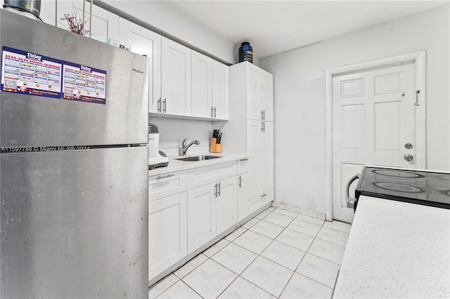 kitchen with white cabinets, sink, stainless steel fridge, and light tile floors