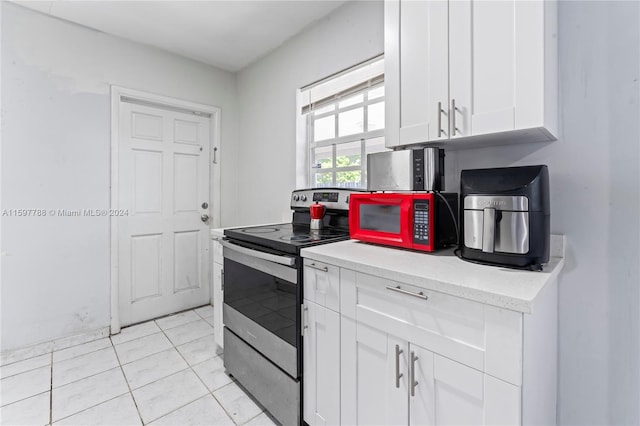 kitchen with stainless steel electric stove, white cabinetry, and light tile floors