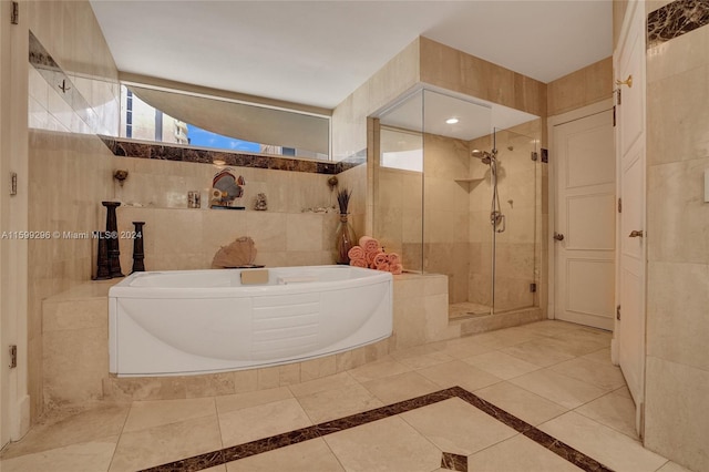 bathroom with shower with separate bathtub and tile walls