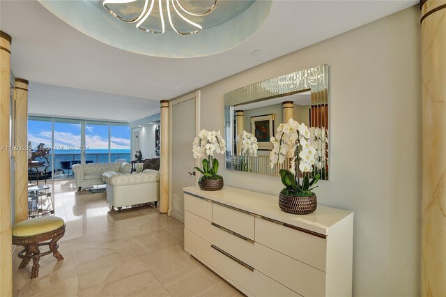 hallway with a water view, expansive windows, and an inviting chandelier