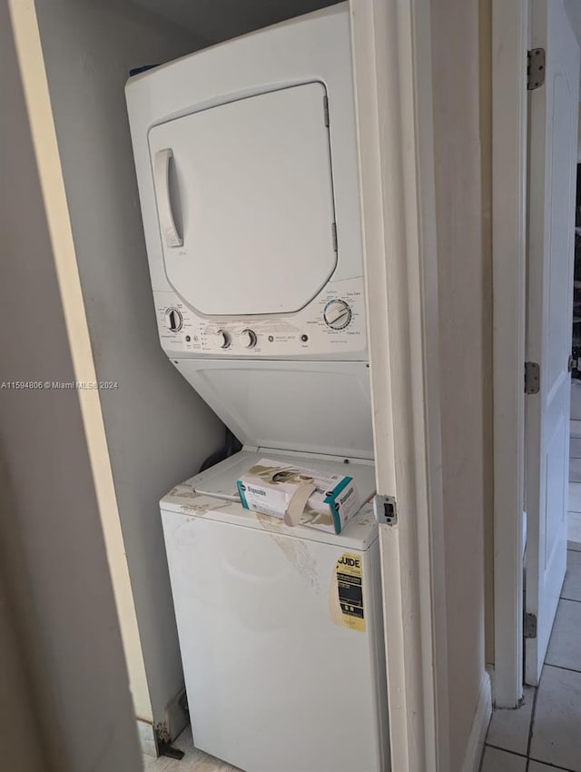 laundry room featuring stacked washer and clothes dryer and light tile floors