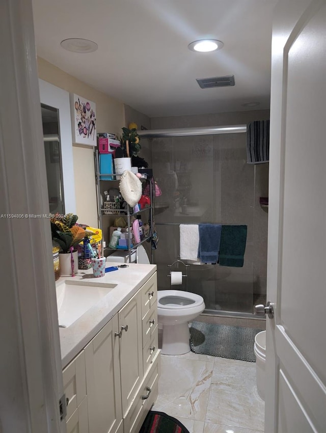 bathroom featuring tile flooring, a shower with shower door, toilet, and vanity