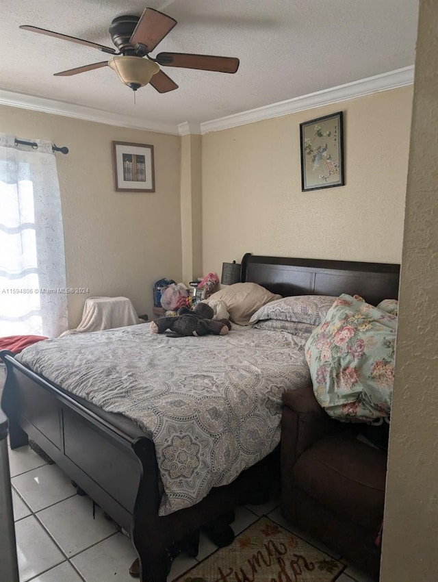 bedroom with tile floors, ceiling fan, a textured ceiling, and ornamental molding