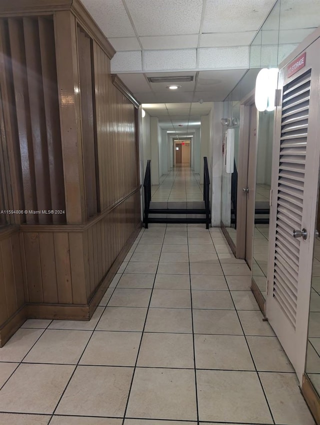 corridor featuring light tile flooring and a drop ceiling