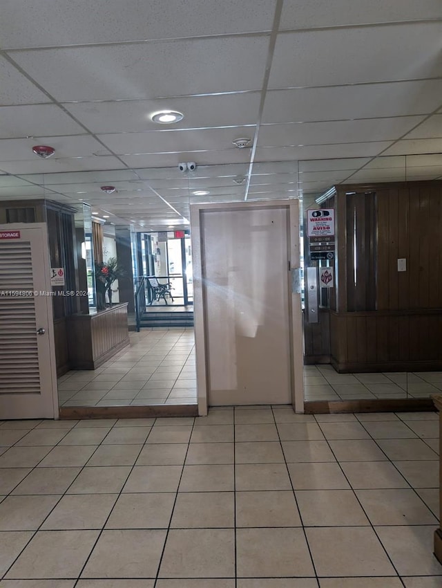 interior space with a drop ceiling, wood walls, and a surveillance system
