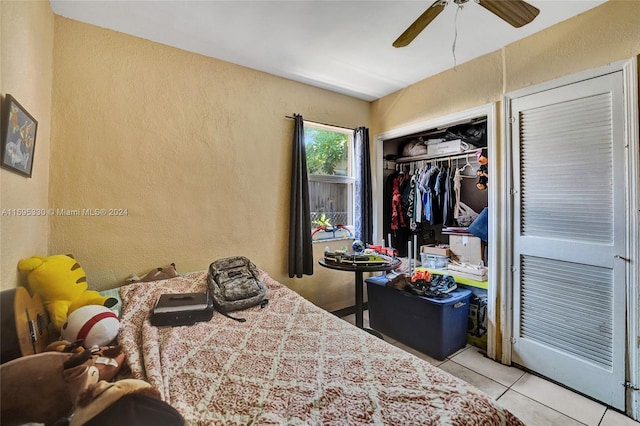 tiled bedroom featuring ceiling fan and a closet