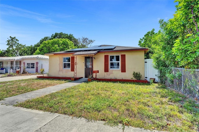 single story home featuring a front yard and solar panels