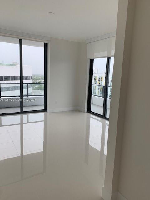 spare room with floor to ceiling windows and baseboards