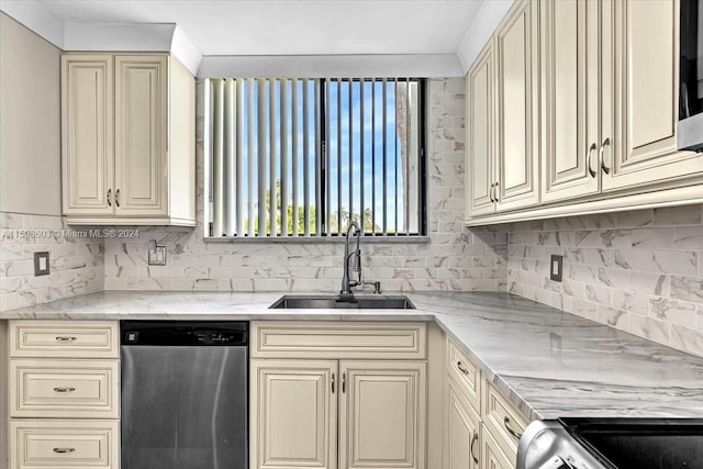 kitchen featuring light stone countertops, stove, stainless steel dishwasher, sink, and cream cabinetry