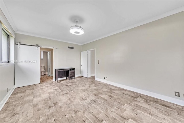 unfurnished bedroom featuring light hardwood / wood-style floors, a barn door, and crown molding