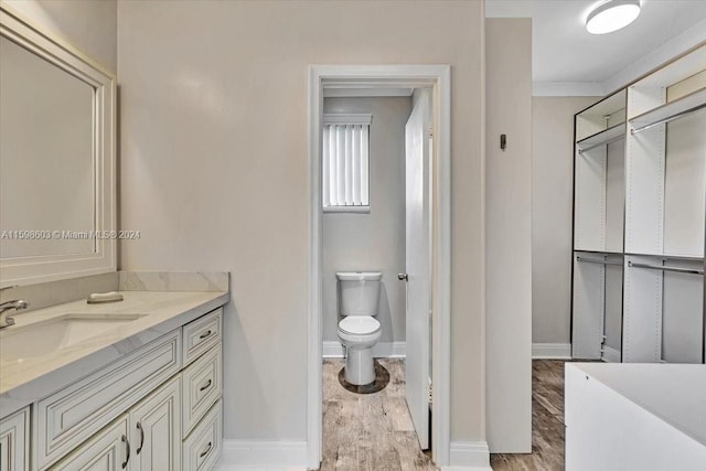 bathroom with vanity, hardwood / wood-style flooring, toilet, and crown molding