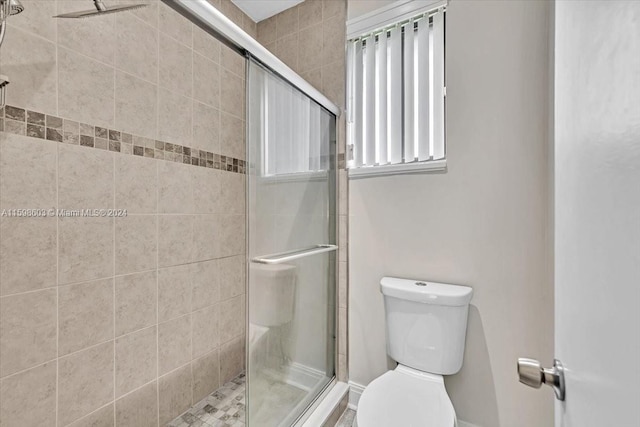 bathroom featuring toilet and a shower with door