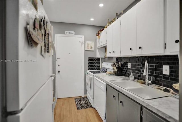 kitchen featuring tasteful backsplash, light wood-type flooring, range, white dishwasher, and sink