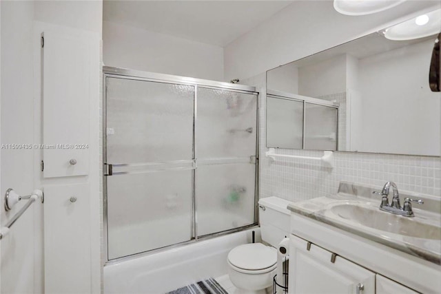 full bathroom with oversized vanity, tasteful backsplash, tile walls, shower / bath combination with glass door, and toilet