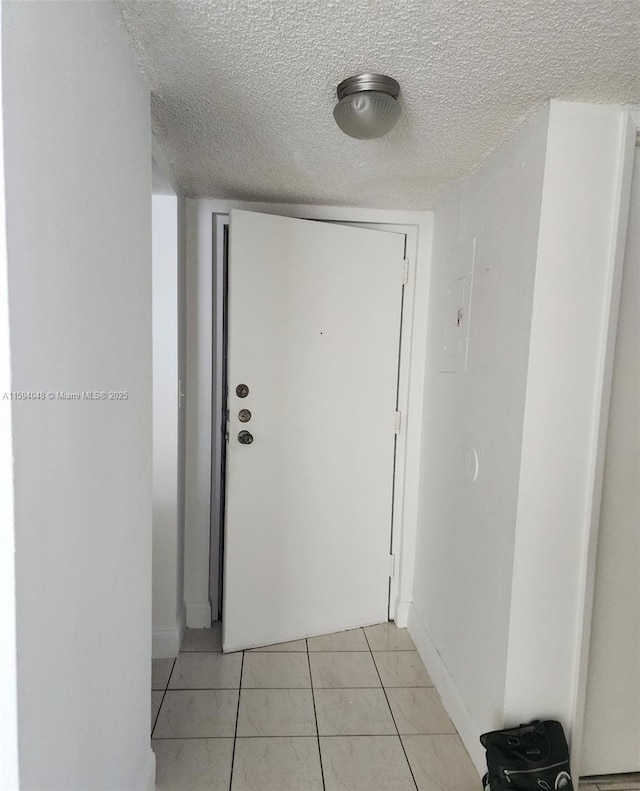 hall with light tile patterned flooring and a textured ceiling