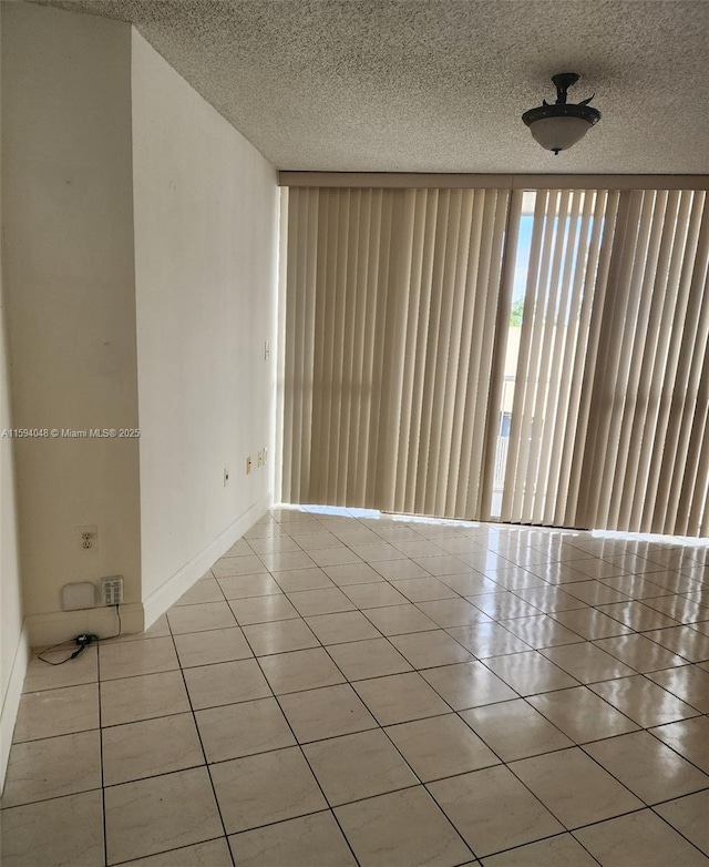 empty room with a textured ceiling and light tile patterned floors