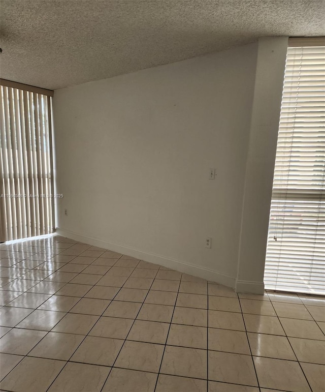 tiled empty room featuring a textured ceiling