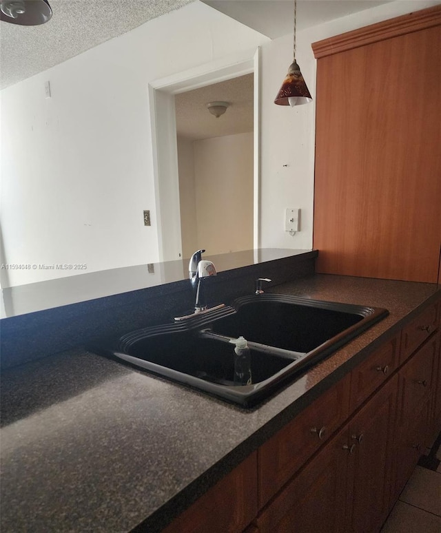 kitchen with a textured ceiling, tile patterned floors, pendant lighting, and sink