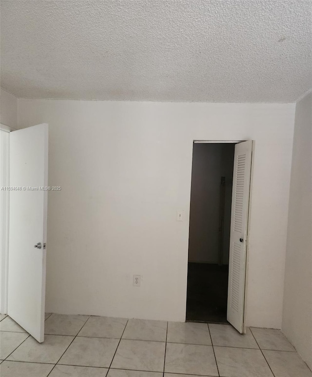 unfurnished room with a textured ceiling and light tile patterned floors