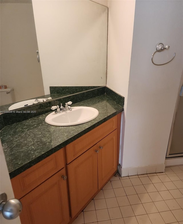 bathroom with toilet, vanity, and tile patterned flooring