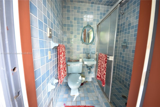 bathroom with toilet, walk in shower, tile walls, tile patterned floors, and sink