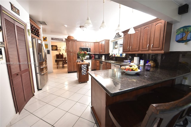 kitchen featuring stainless steel appliances, dark stone counters, a kitchen island, decorative backsplash, and light tile patterned flooring