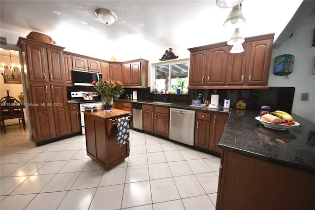 kitchen featuring stainless steel appliances, sink, light tile patterned flooring, decorative backsplash, and a kitchen island