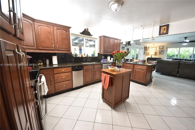 kitchen featuring sink, ceiling fan, light tile patterned floors, backsplash, and a kitchen island