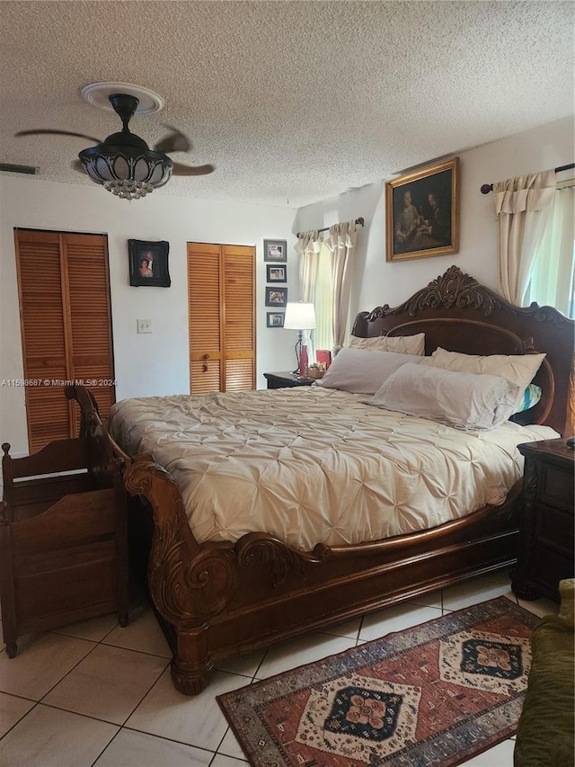 bedroom with a textured ceiling, ceiling fan, light tile patterned floors, and multiple windows