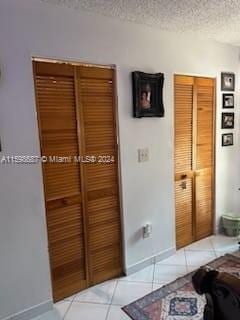 hall featuring a textured ceiling and light tile patterned floors