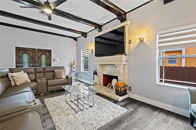 living room featuring beam ceiling, dark hardwood / wood-style floors, ceiling fan, and a premium fireplace