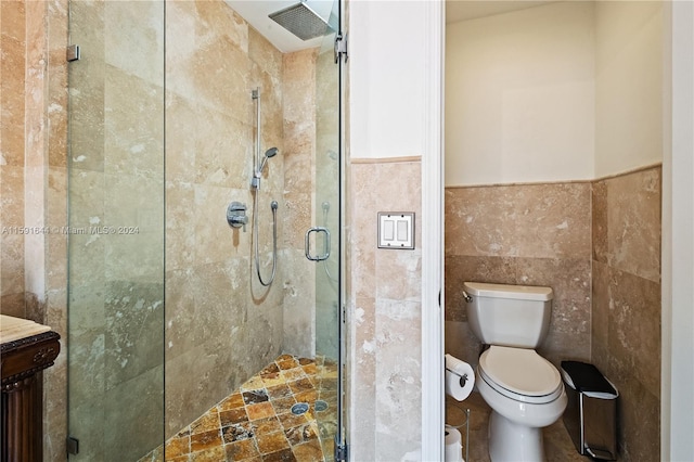 bathroom with tile walls, vanity, toilet, and a shower with door