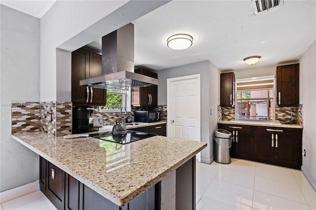 kitchen with black appliances, a healthy amount of sunlight, island range hood, and backsplash