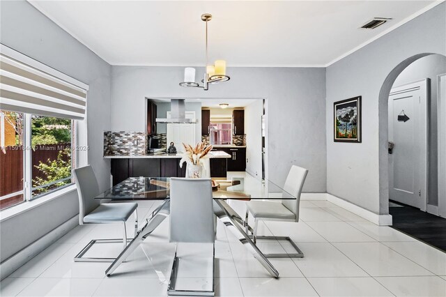 tiled dining room with crown molding and a notable chandelier