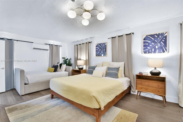 bedroom with hardwood / wood-style flooring and a wall unit AC