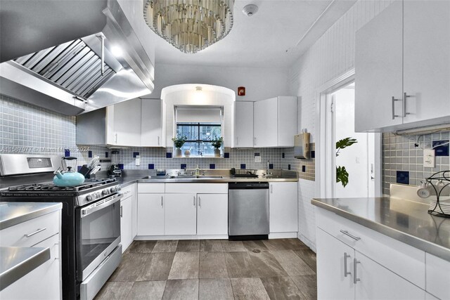 kitchen featuring stainless steel counters, range hood, white cabinetry, stainless steel appliances, and backsplash