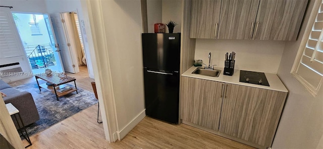 kitchen featuring sink, light hardwood / wood-style flooring, and black appliances