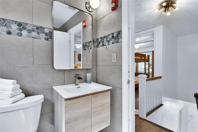 bathroom with toilet, tile walls, wood-type flooring, and vanity